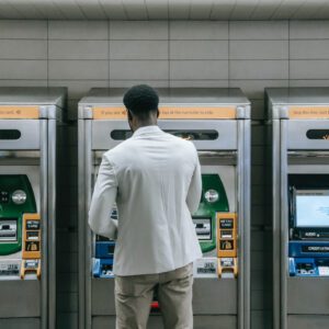 A man standing in front of three atm machines.