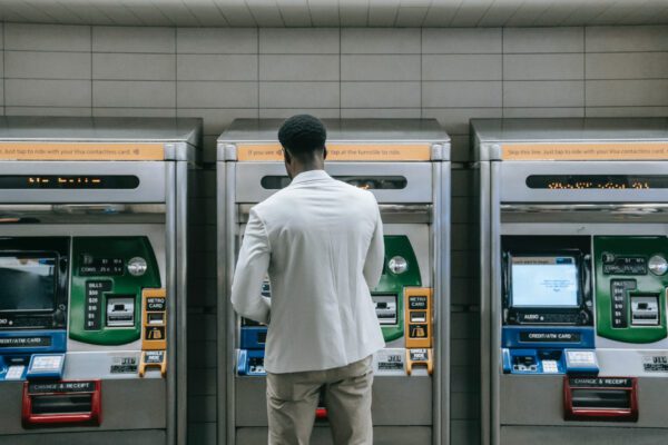 A man standing in front of three atm machines.