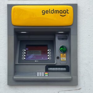 A yellow and grey atm machine on the wall.
