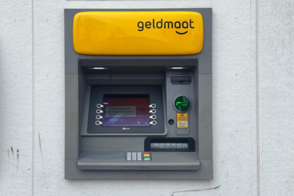 A yellow and grey atm machine on the wall.