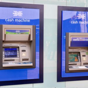 Two atm machines are shown on a wall.