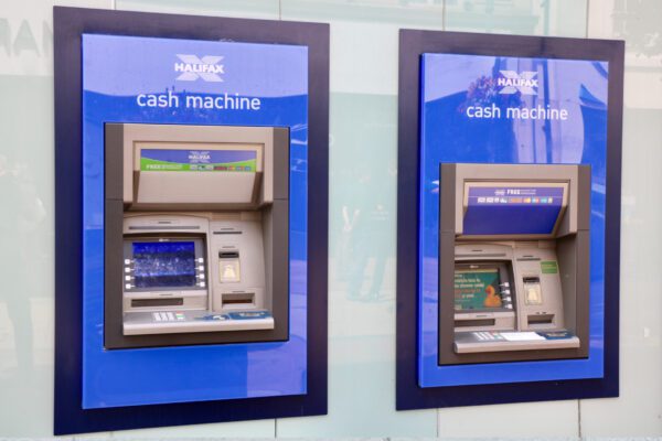 Two atm machines are shown on a wall.